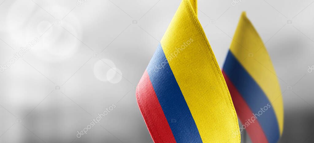 Small national flags of the Colombia on a light blurry background