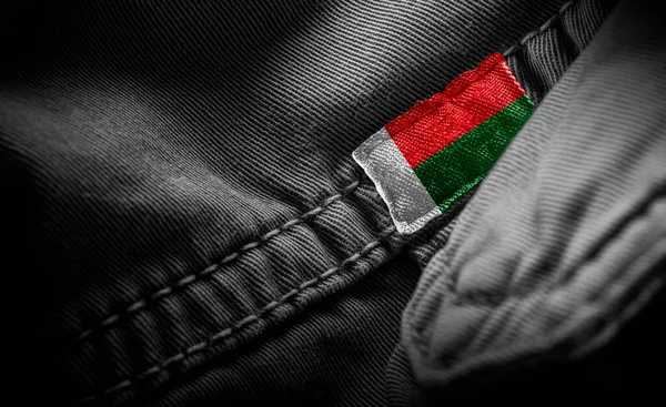 Tag on dark clothing in the form of the flag of the Madagascar — Stock Photo, Image