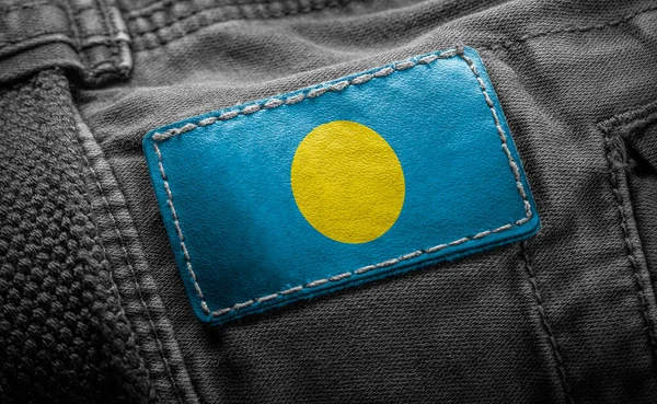 Etiqueta en la ropa oscura en forma de la bandera del Palau —  Fotos de Stock
