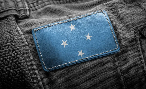 Tag on dark clothing in the form of the flag of the Federated States Micronesia — Stock Photo, Image