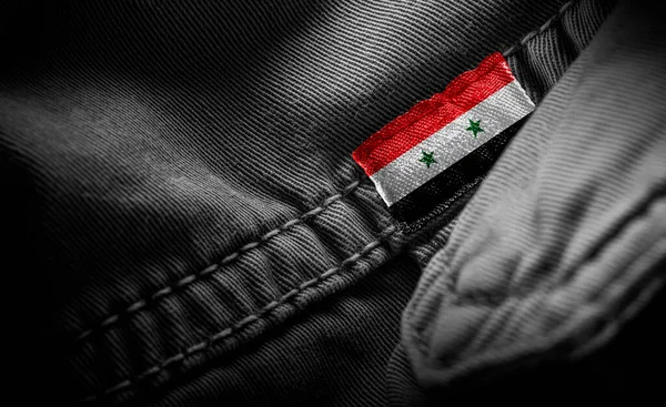 Étiquette sur vêtements sombres sous la forme du drapeau de la Syrie — Photo