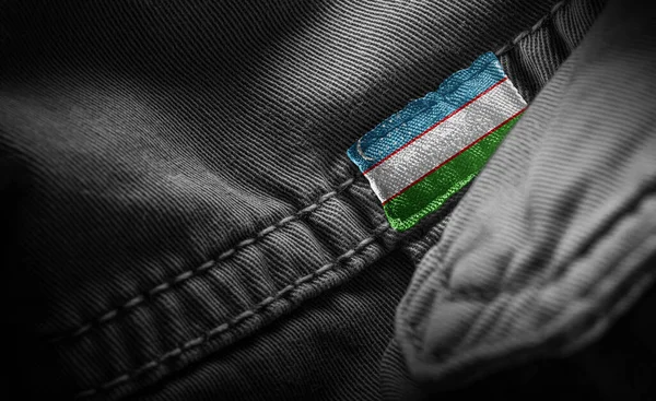 Tag na roupa escura sob a forma da bandeira do Uzbequistão — Fotografia de Stock