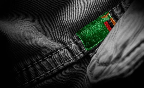 Etiqueta en la ropa oscura en forma de la bandera de Zambia — Foto de Stock