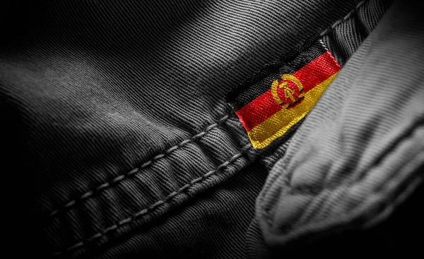Koyu renk giysileri Doğu Almanya bayrağı şeklinde etiketle. — Stok fotoğraf