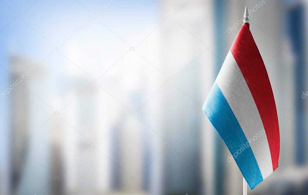 A small flag of Luxembourg on the background of a blurred background