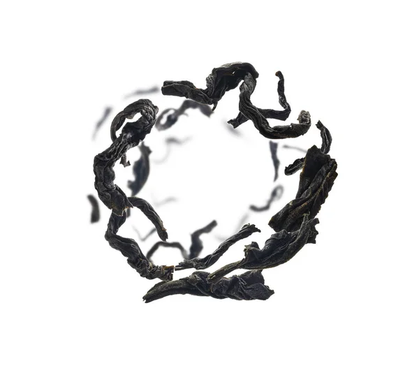 Сушеный черный чай вблизи левитации на белом фоне — стоковое фото