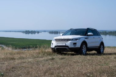 Range Rover Evoque arabası Tataristan Cumhuriyeti 'nde Kama Nehri' nin arka planında bir tepenin üzerinde duruyor. 19 Ağustos 2021 'de güneşli bir gün.