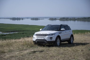 Range Rover Evoque arabası Tataristan Cumhuriyeti 'nde Kama Nehri' nin arka planında bir tepenin üzerinde duruyor. 19 Ağustos 2021 'de güneşli bir gün.