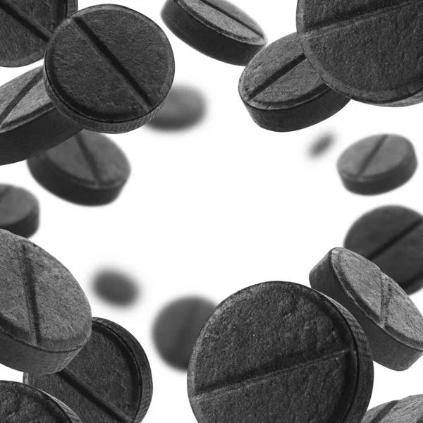 Siyah etkinleştirilmiş karbon tabletleri beyaz arkaplanda uçar — Stok fotoğraf