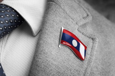 Takım elbise yakasında Laos bayrağı olan metal bir rozet.
