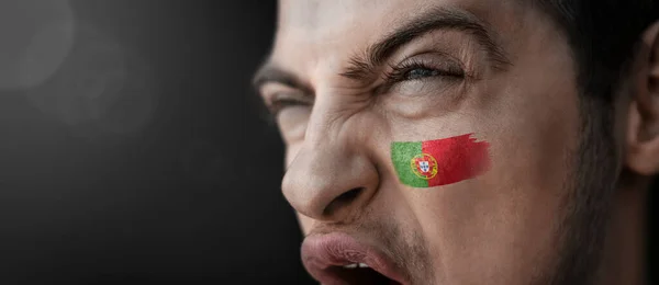 Un hombre gritando con la imagen de la bandera nacional de Portugal en su cara — Foto de Stock