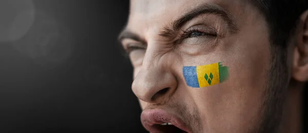 Un hombre gritando con la imagen de la bandera nacional de San Vicente en su rostro —  Fotos de Stock