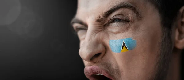 A screaming man with the image of the Saint Lucia national flag on his face — Stock Photo, Image