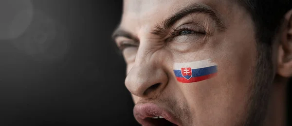 A screaming man with the image of the Slovakia national flag on his face — Stock Photo, Image