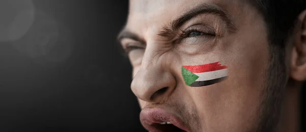 A screaming man with the image of the Sudan national flag on his face — Stock Photo, Image
