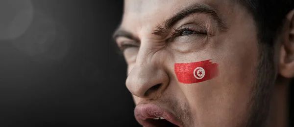 A screaming man with the image of the Tunisia national flag on his face — Stock Photo, Image