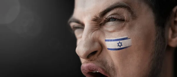 Un hombre gritando con la imagen de la bandera nacional de Israel en su rostro — Foto de Stock