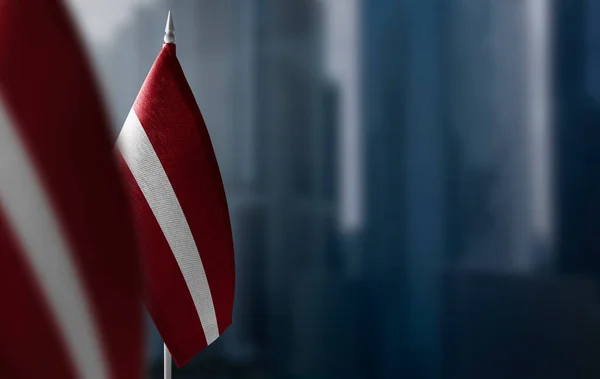 Невеликі прапори Латвії на розмитому тлі міста. — стокове фото