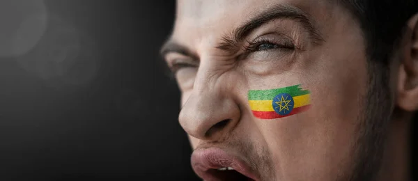 Un uomo urlante con l'immagine della bandiera nazionale etiope sul volto — Foto Stock