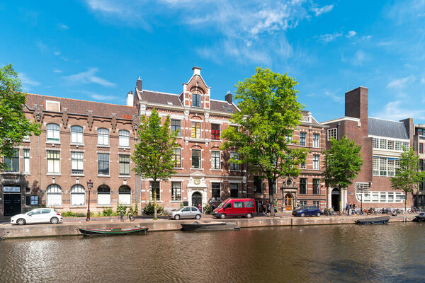Amsterdam, Netherlands- June 30, 2019: Embankment of canal with traditional houses in the capital of the Netherlands.