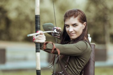 Ormanın arka planında genç kadın okçuluğunun portresi.