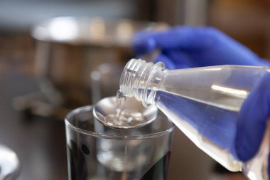 Yakın plan. Kadın plastik şişeden cam bardağa su dolduruyor.