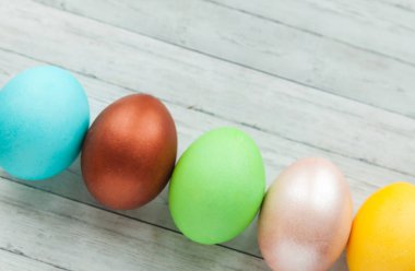 Hafif ahşap arka planda renkli Paskalya yumurtaları.