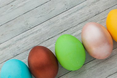 Hafif ahşap arka planda renkli Paskalya yumurtaları.