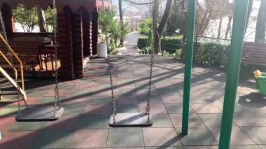 Oyun alanı baharda kapalı, yakın çekim, salıncak hareket ediyor.