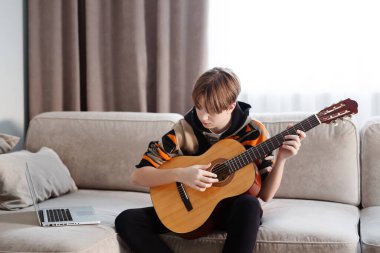 Evde gitar çalan bir çocuk, online ders. Yüksek kaliteli video