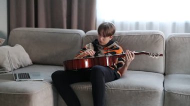 Evde gitar çalan bir çocuk, online ders. Yüksek kaliteli video