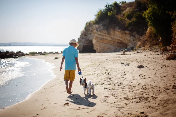 Bello giovane ragazzo e cane che camminano insieme sulla spiaggia — Foto Stock