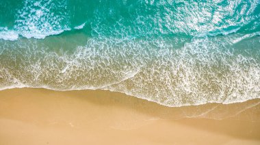 Metnin için fotokopi alanı olan turkuaz suyla çarpıcı güzellikteki deniz manzaralı bir kumsalın insansız hava görüntüsü. Turkuaz suyu ve insansız hava aracı görüntüsü olan güzel bir kumsal.