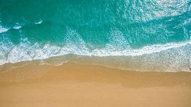 Metnin için fotokopi alanı olan turkuaz suyla çarpıcı güzellikteki deniz manzaralı bir kumsalın insansız hava görüntüsü. Turkuaz suyu ve insansız hava aracı görüntüsü olan güzel bir kumsal.