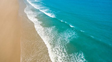 Metnin için fotokopi alanı olan turkuaz suyla çarpıcı güzellikteki deniz manzaralı bir kumsalın insansız hava görüntüsü. Turkuaz suyu ve insansız hava aracı görüntüsü olan güzel bir kumsal.
