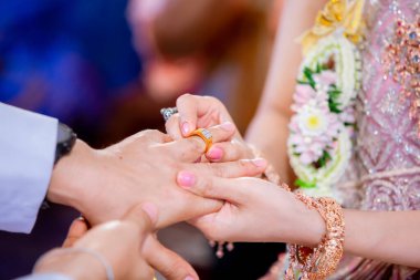 Evlilik yüzükleri. Nikah yüzüğünü He 'ye taktı. Gelin, Yüzüğü Damada Giydir. Thai düğün töreni ve Tayland düğün süsü. Gelin, damadın parmağına yüzüğü tak..