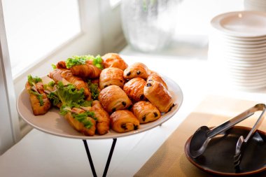 Lokanta büfesi yemek masasında çikolatalı çörek. Yemek masasında leziz yemekler var. Düğünde bir yığın kruvasan sandviçi