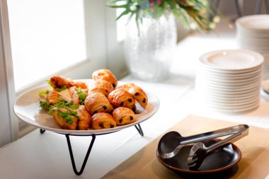 Lokanta büfesi yemek masasında çikolatalı çörek. Yemek masasında leziz yemekler var. Düğünde bir yığın kruvasan sandviçi