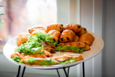Lokanta büfesi yemek masasında çikolatalı çörek. Yemek masasında leziz yemekler var. Düğünde bir yığın kruvasan sandviçi