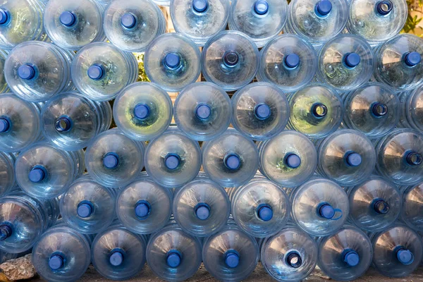 Plastic water bottle background, blue bottle caps, orderly arrangement. Empty bottles for drinking water. Heap of empty plastic drinking water bottles.  clear bottles when poured out of water.