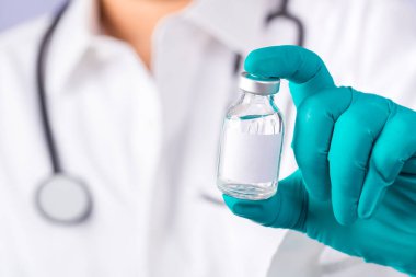 Omzunda steteskop olan bir doktor şırınga ve COVID-19 aşısı taşıyor. Sağlık ve Tıp Konsepti. Coronavirus aşısı COVID-19 'un geliştirilmesi ve yaratılması. Coronavirus Aşısı.
