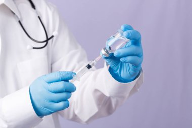 Omzunda steteskop olan bir doktor şırınga ve COVID-19 aşısı taşıyor. Sağlık ve Tıp Konsepti. Coronavirus aşısı COVID-19 'un geliştirilmesi ve yaratılması. Coronavirus Aşısı.