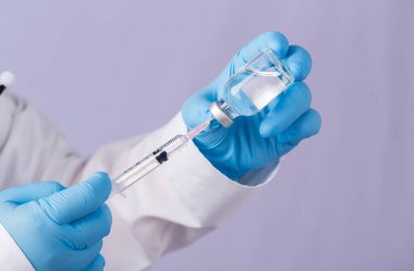 Omzunda steteskop olan bir doktor şırınga ve COVID-19 aşısı taşıyor. Sağlık ve Tıp Konsepti. Coronavirus aşısı COVID-19 'un geliştirilmesi ve yaratılması. Coronavirus Aşısı.