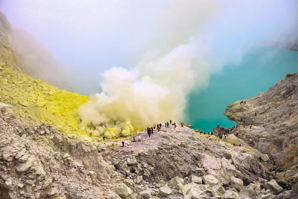 Crater of a volcano with a green sulfuric volcanic lake and volcanic smoke. View of the smoking volcano Kawah Ijen in Indonesia. Mountain landscape Extracting Sulphur inside Kawah Ijen crater