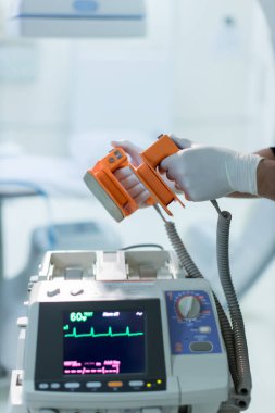 Doktor hastanede hastanın hayatını kurtarmak için bir defibrilatörler veriyor. 