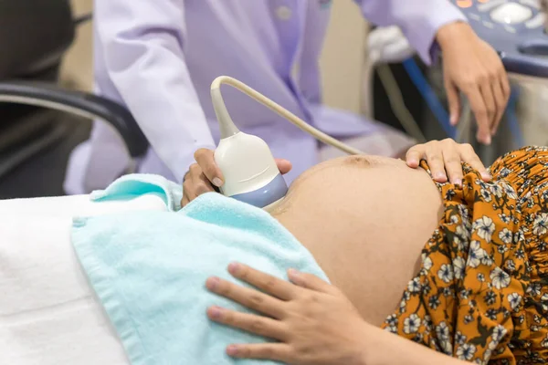 Pregnant woman getting ultrasound from doctor. Doctor screening of pregnant woman by ultrasound. Doctor makes the patient women abdominal ultrasound.