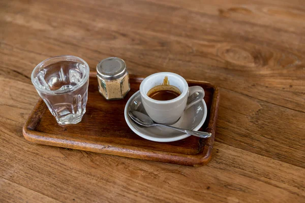 black drip coffee in glass cup. Cup of espresso coffee. Grey cup of black coffee on grey wooden desk or table.