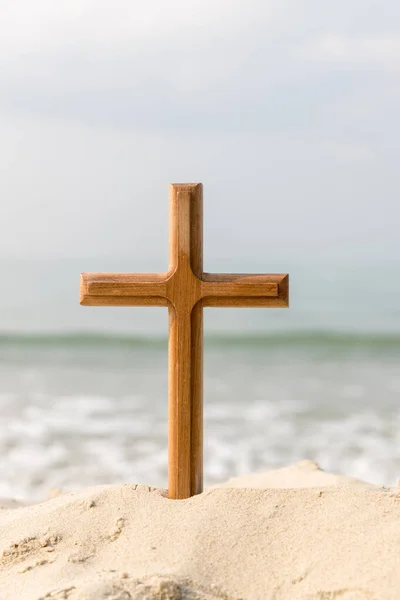 Wooden cross on the beach of the  Sea background. Easter concept. Concept  cross religion symbol in grass over sunset or sunrise sky.