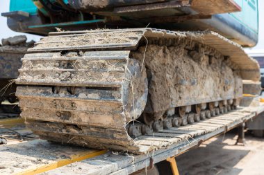 Kazı araçlarının izleri. Yoldaki traktörün buldozerinin eski demir tırtılları. Buldozer tırtıl izleri. Tekerlekleri yerde olan siyah tırtıl traktörü..