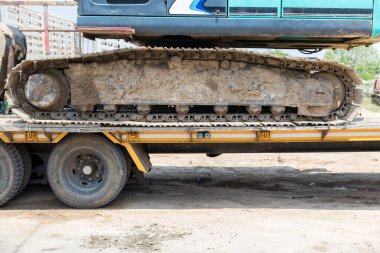 Kazı araçlarının izleri. Yoldaki traktörün buldozerinin eski demir tırtılları. Buldozer tırtıl izleri. Tekerlekleri yerde olan siyah tırtıl traktörü..